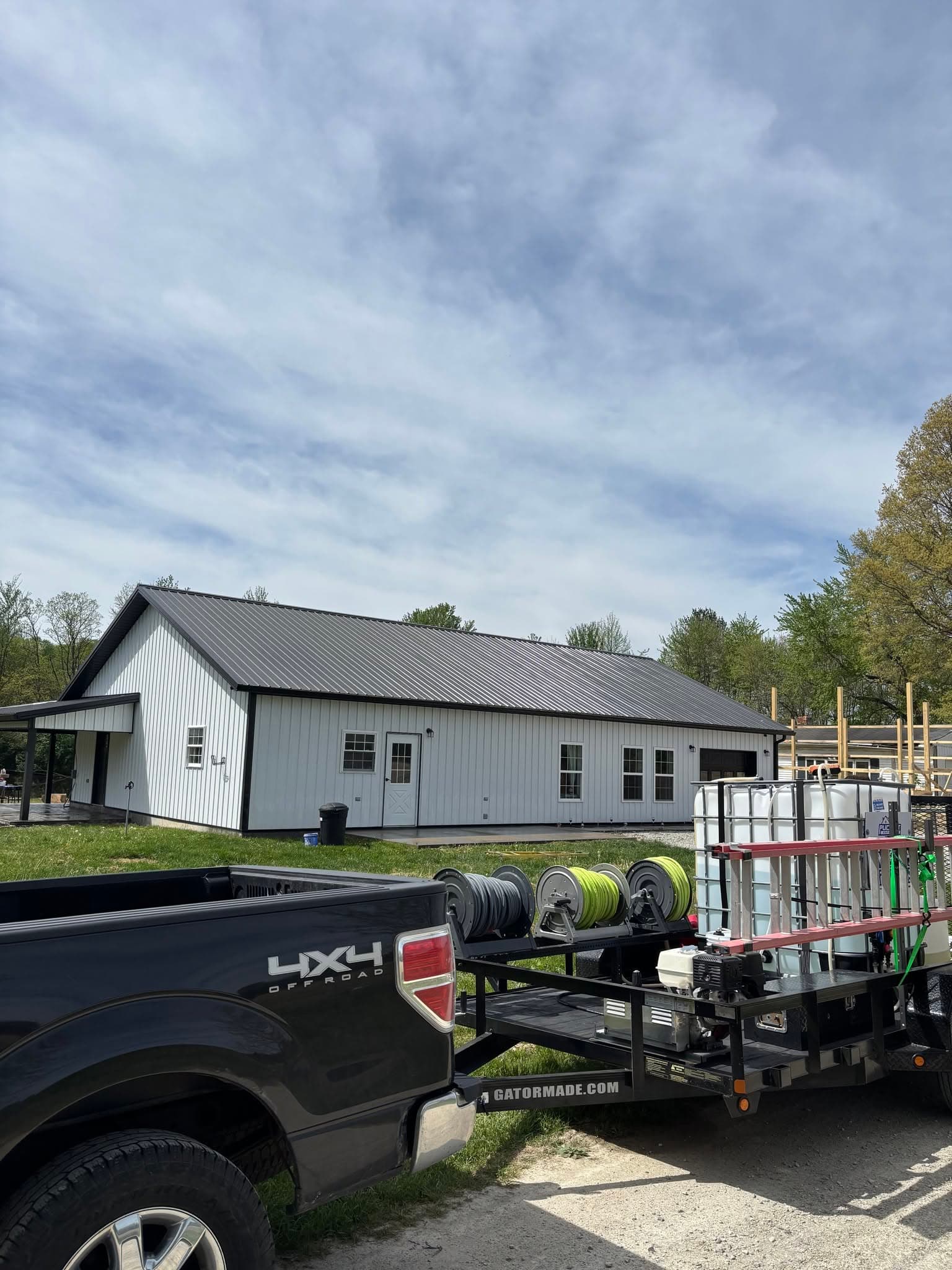 Puckett Exteriors truck and equipment trailer parked beside a white metal barndominium