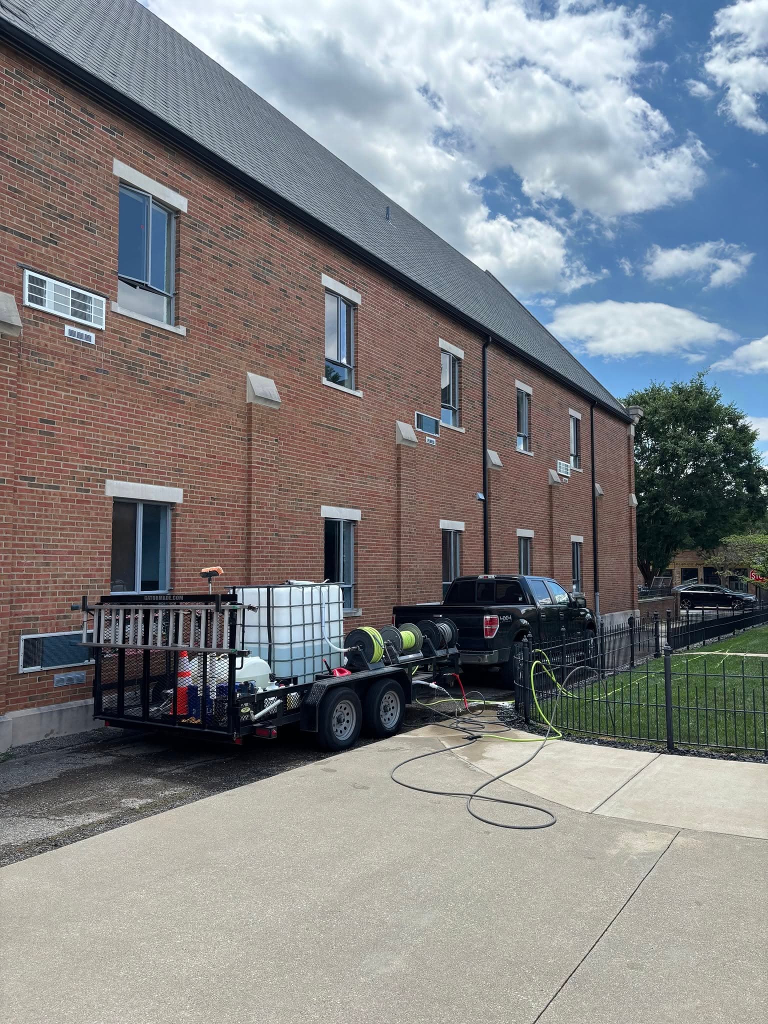 Puckett Exteriors truck and pressure washing trailer set up alongside a large two-story brick building for a commercial wash