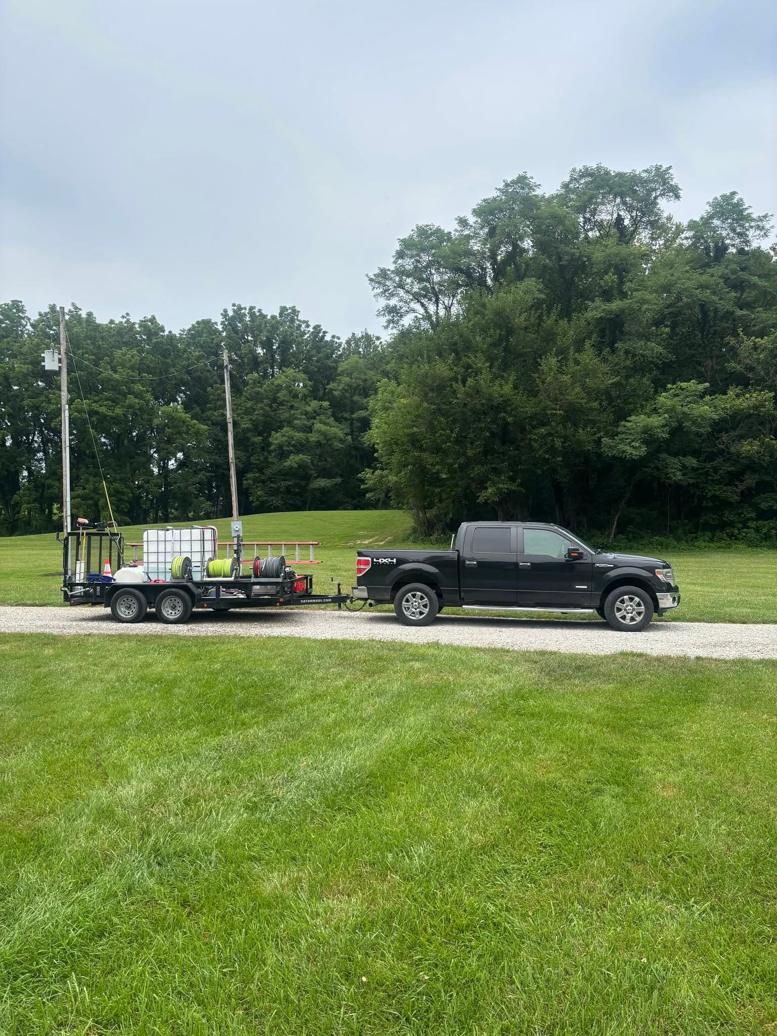 Puckett Exteriors black pickup truck towing a pressure washing equipment trailer on a gravel drive
