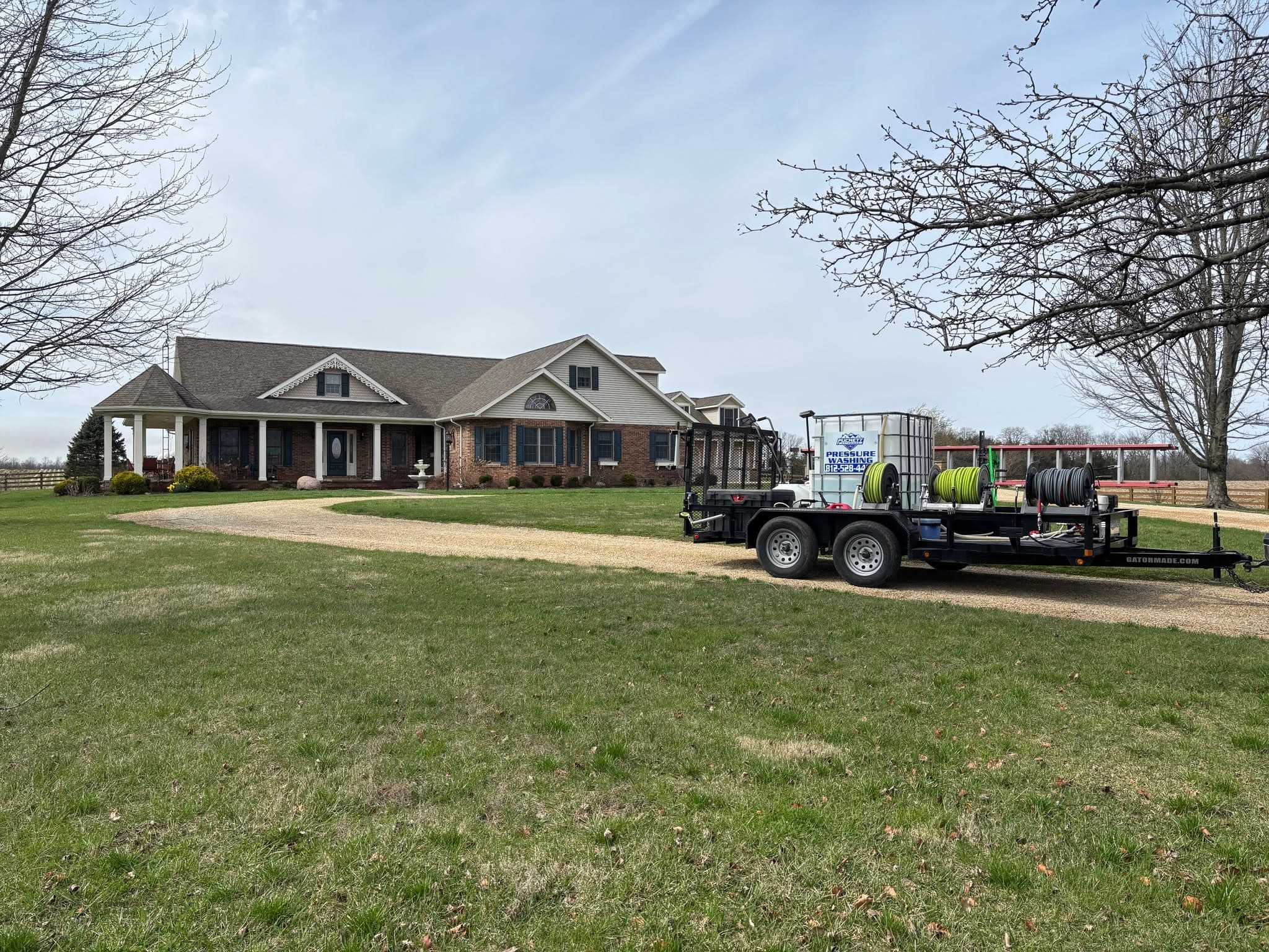 Puckett Exteriors branded pressure washing trailer parked in the driveway of a large country ranch home